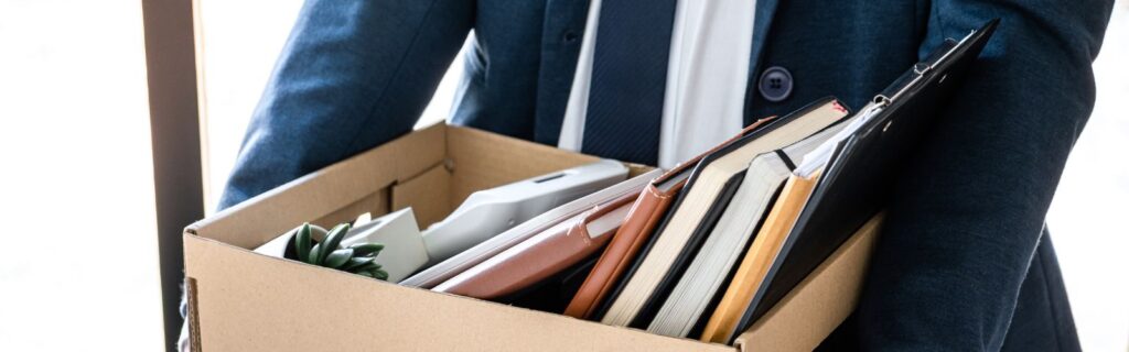 Homem demitido levando seus objetos pessoais em caixa de papelão.
