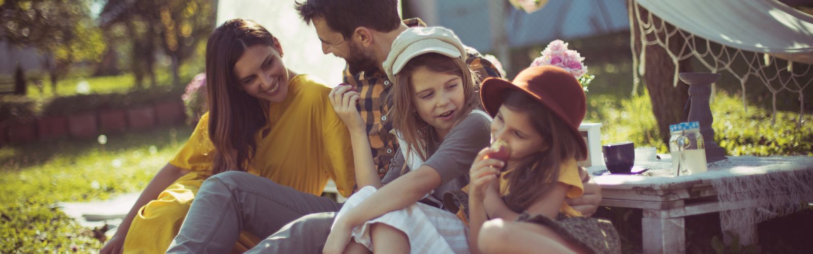 Família reunida fazendo piquenique em um jardim arborizado, simbolizando união e tranquilidade na proteção do patrimônio da sua família com segurança.