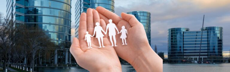 Mãos segurando silhuetas de uma família sobre fundo de edifícios comerciais modernos. Holding familiar e empresarial: quando vale a pena criar uma?